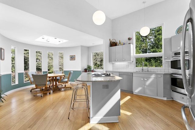 kitchen with light wood finished floors, a center island, stainless steel appliances, and a sink