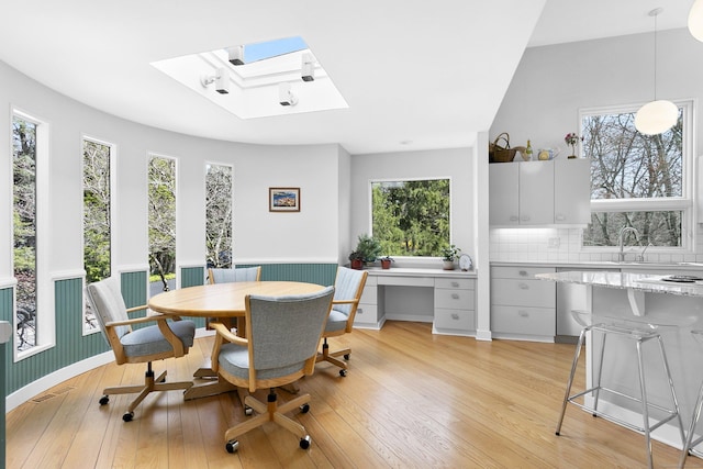 dining space featuring a skylight, light wood finished floors, and plenty of natural light