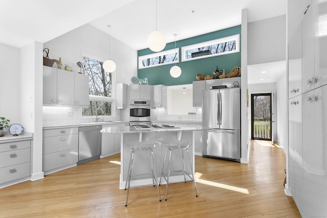 kitchen featuring a breakfast bar, a high ceiling, appliances with stainless steel finishes, and decorative backsplash