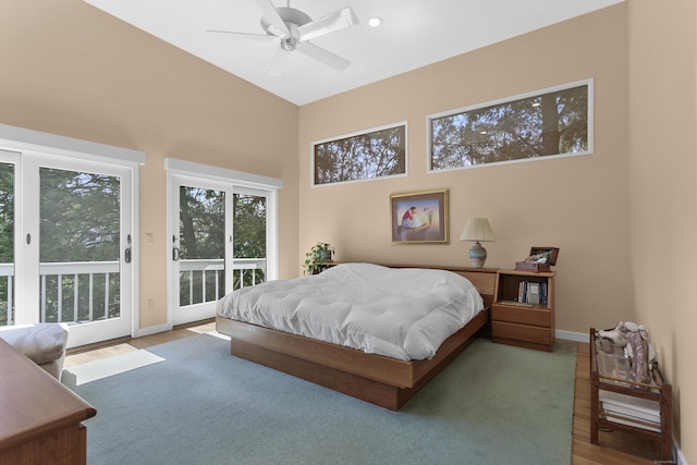 bedroom featuring ceiling fan, access to exterior, wood finished floors, a high ceiling, and baseboards
