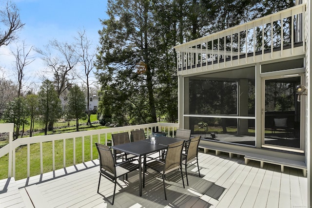 wooden terrace featuring outdoor dining area and a lawn