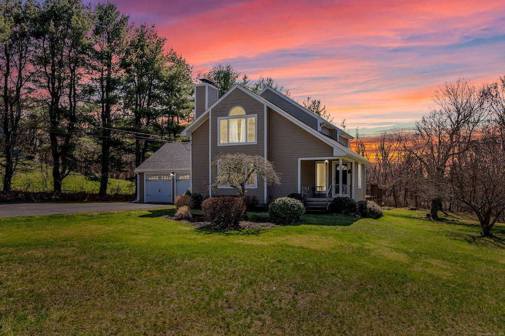 exterior space with a garage, a front yard, driveway, and a chimney