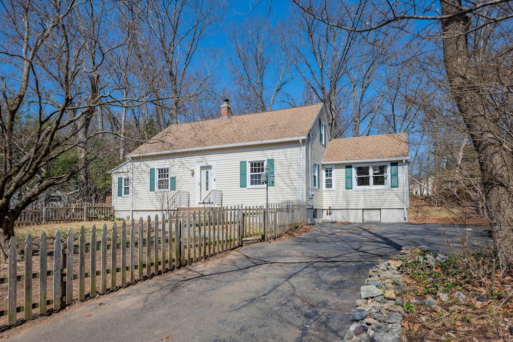 7 N Forest Cir, West Haven, CT 06516 - view of front facade with a chimney, a shingled roof, a fenced front yard, and driveway