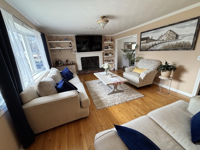 living area featuring built in features, baseboards, ornamental molding, and hardwood / wood-style flooring