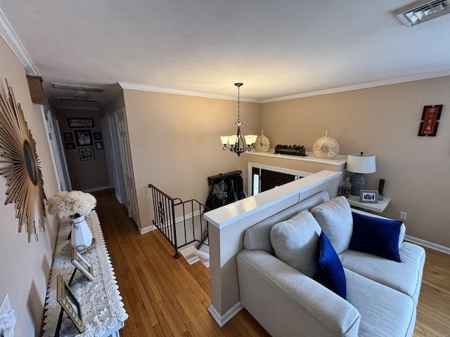 living area featuring crown molding, wood-type flooring, a chandelier, and visible vents