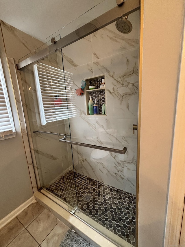 bathroom with a marble finish shower and baseboards