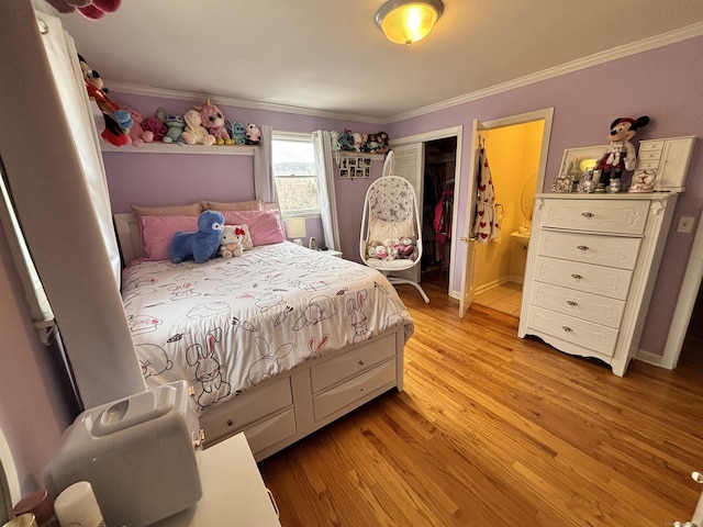 bedroom featuring light wood-type flooring, a closet, crown molding, and ensuite bath