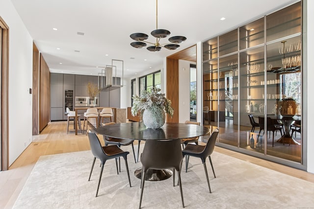 dining area with light wood finished floors, plenty of natural light, a chandelier, and recessed lighting