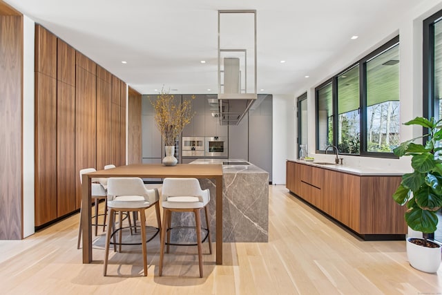 kitchen featuring modern cabinets, brown cabinets, stainless steel oven, light wood-style floors, and recessed lighting