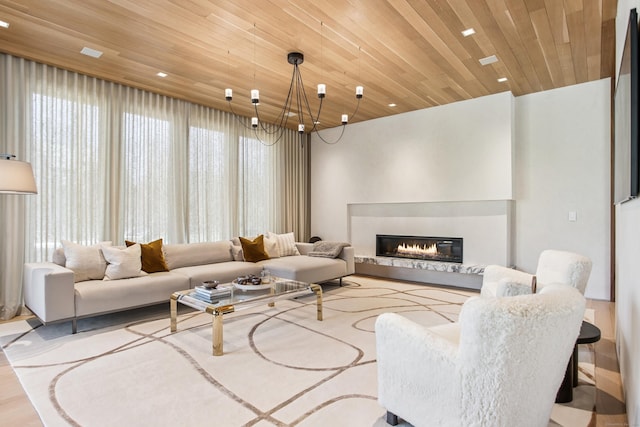 living room featuring wood ceiling, a chandelier, a glass covered fireplace, wood finished floors, and recessed lighting