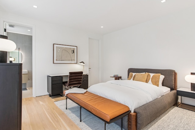 bedroom featuring light wood-type flooring, recessed lighting, a desk, and ensuite bath