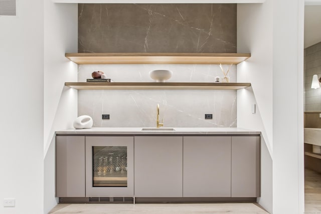 indoor wet bar with light wood-type flooring and wine cooler
