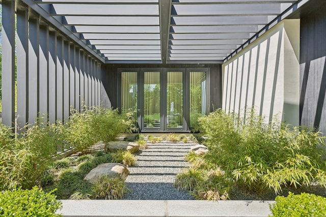 view of exterior entry with french doors, a pergola, and board and batten siding
