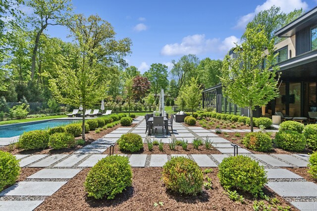surrounding community with a patio area, a swimming pool, view of scattered trees, and fence