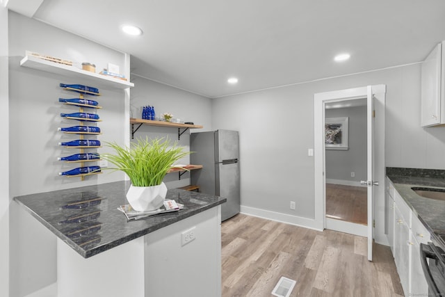 kitchen featuring white cabinets, open shelves, light wood-style floors, freestanding refrigerator, and visible vents