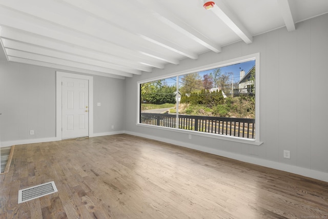 unfurnished living room featuring baseboards, beamed ceiling, wood finished floors, and visible vents