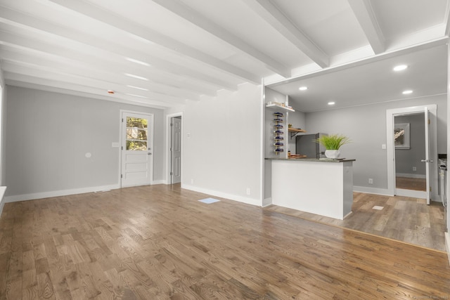 unfurnished living room featuring baseboards, beamed ceiling, recessed lighting, and wood finished floors