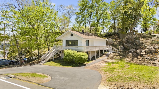 beach home featuring stairs, a chimney, and aphalt driveway