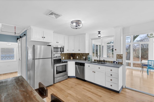 37 Woodland Dr, Old Saybrook, CT 06475 - kitchen with appliances with stainless steel finishes, a sink, a barn door, and white cabinets