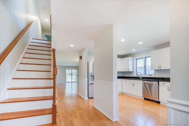 stairs with a healthy amount of sunlight, wainscoting, recessed lighting, and wood finished floors