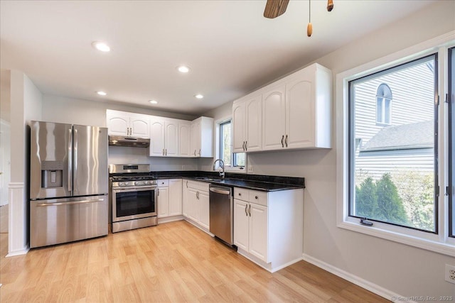 kitchen with under cabinet range hood, stainless steel appliances, white cabinets, and a sink