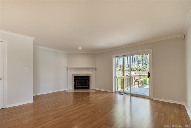 unfurnished living room featuring baseboards, a fireplace, crown molding, and wood finished floors