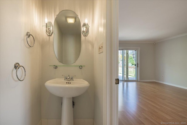 bathroom featuring baseboards, ornamental molding, and wood finished floors