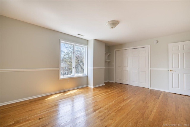 unfurnished bedroom featuring light wood-style flooring, baseboards, and visible vents