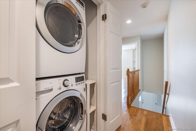 laundry room with recessed lighting, laundry area, wood finished floors, and stacked washer and dryer