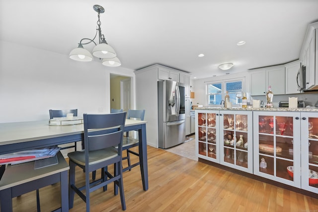 105 Valley Rd, Westport, CT 06880 - kitchen featuring stainless steel refrigerator with ice dispenser, a chandelier, light wood-type flooring, white cabinetry, and pendant lighting