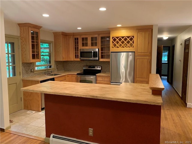 kitchen with a sink, backsplash, light countertops, and appliances with stainless steel finishes