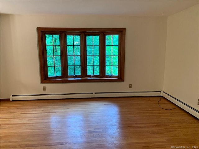 spare room featuring a baseboard heating unit and wood finished floors