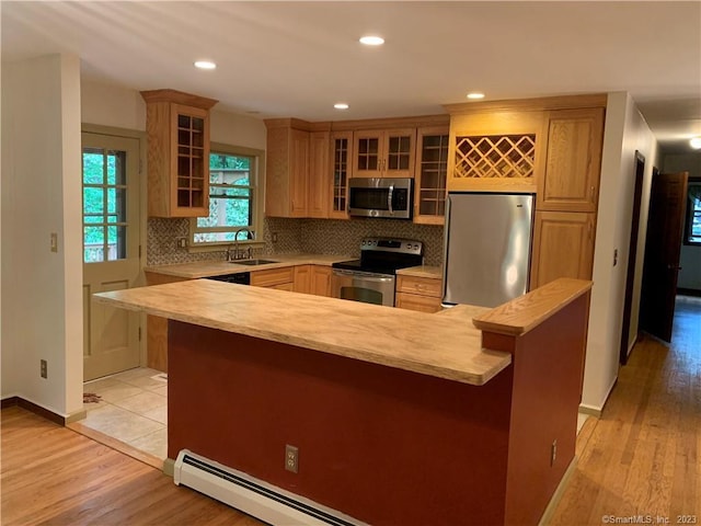 kitchen with stainless steel appliances, light countertops, a sink, and decorative backsplash
