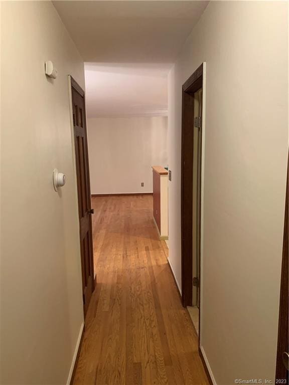 corridor with light wood-style flooring and baseboards