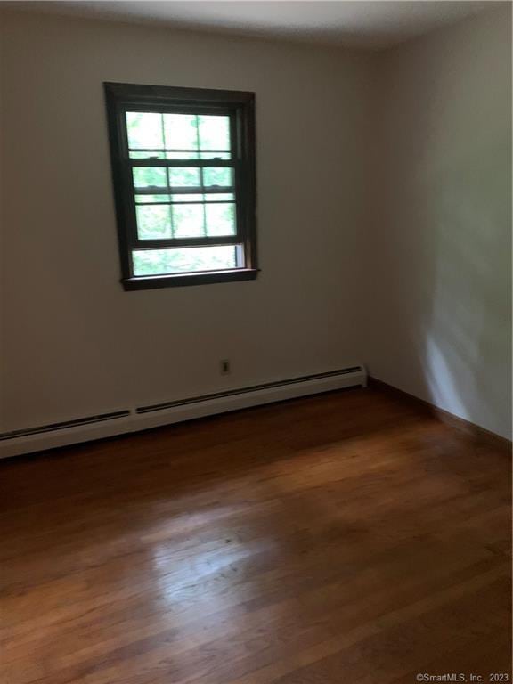 unfurnished room featuring wood finished floors and baseboard heating