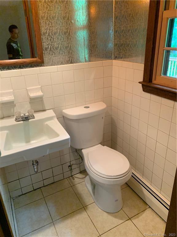 bathroom with tile patterned floors, a baseboard heating unit, a sink, and toilet