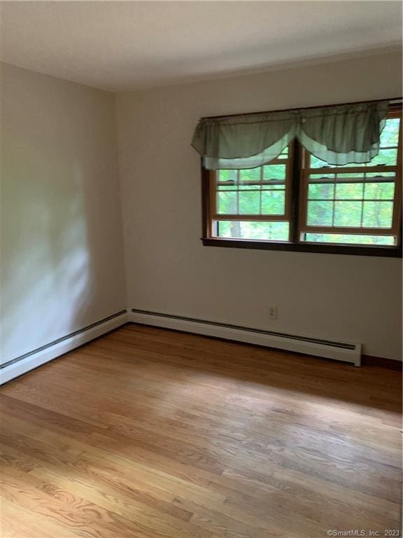 spare room featuring a baseboard radiator and wood finished floors