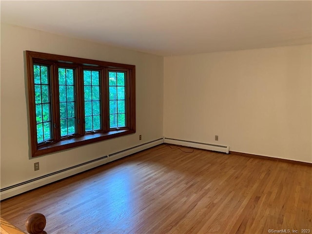 empty room featuring baseboards, light wood-style floors, and baseboard heating