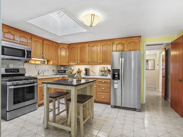 48 Meyer Pl, Greenwich, CT 06878 - kitchen with a sink, stainless steel appliances, a skylight, and brown cabinets
