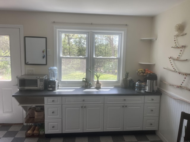kitchen featuring dark countertops, a toaster, white cabinets, and dark floors