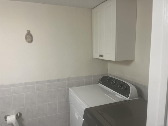 washroom featuring cabinet space and washer and clothes dryer
