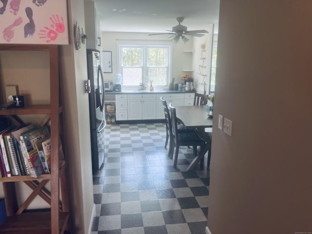 kitchen with stainless steel refrigerator with ice dispenser, ceiling fan, white cabinets, and dark floors