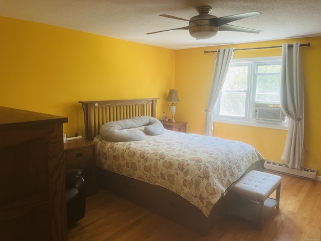 bedroom featuring wood finished floors, ceiling fan, a textured ceiling, cooling unit, and a baseboard radiator