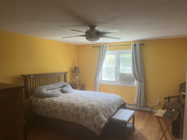 bedroom featuring cooling unit, a textured ceiling, a ceiling fan, wood finished floors, and a baseboard radiator