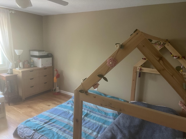 bedroom featuring baseboards, light wood-style flooring, and ceiling fan
