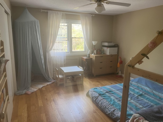 bedroom featuring ceiling fan, light wood-type flooring, and a textured ceiling