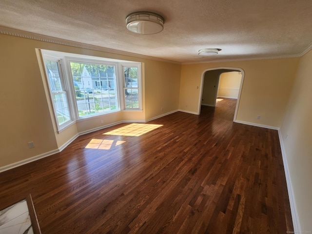 empty room with crown molding, arched walkways, a textured ceiling, and dark wood-type flooring