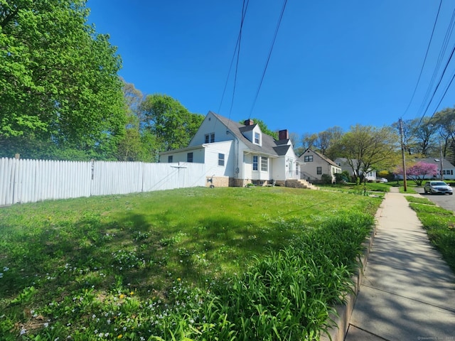 view of side of property with a yard, fence, and a chimney