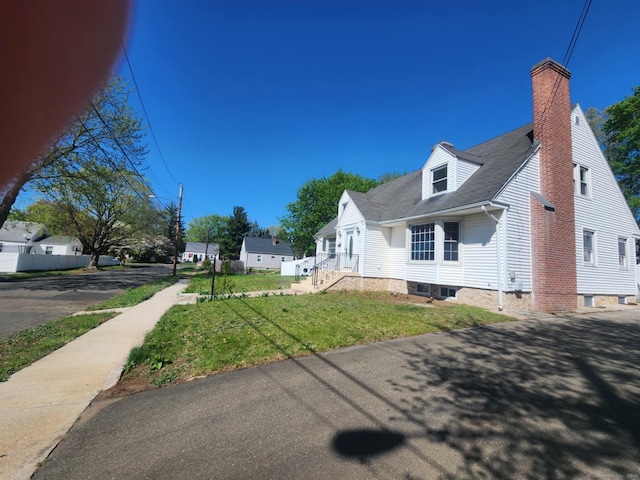 view of home's exterior with a chimney and a yard