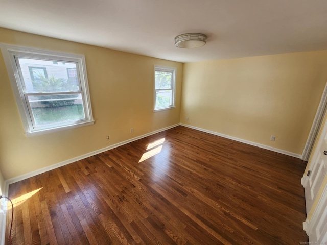 unfurnished room with dark wood-type flooring and baseboards